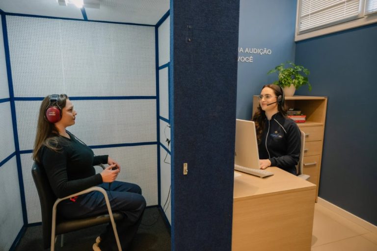 Paciente em cabine acústica durante exame de audiometria na Clínica Amplific
